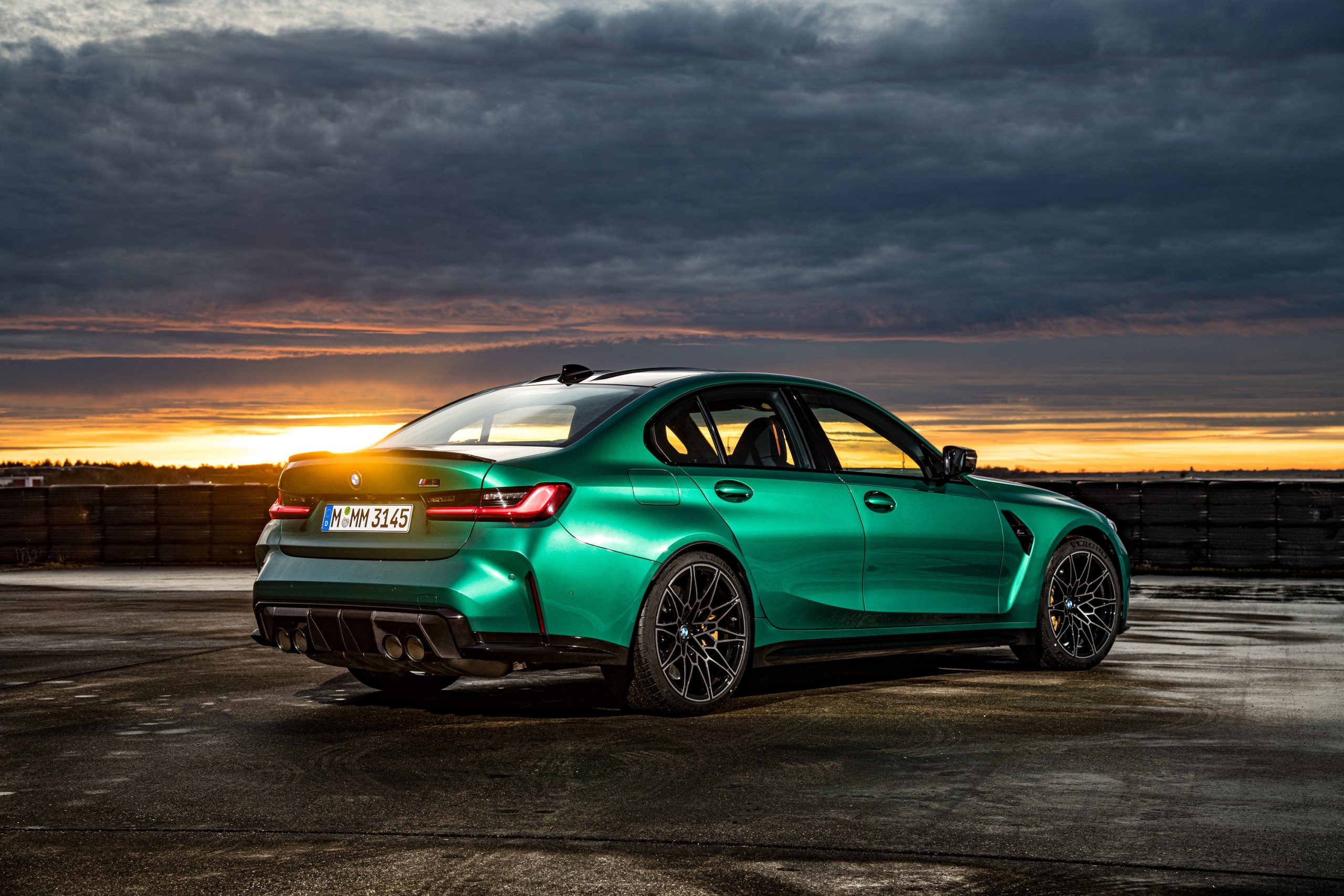 The rear 3/4 of an Isle of Man green BMW M3 shot at sunset on a runway