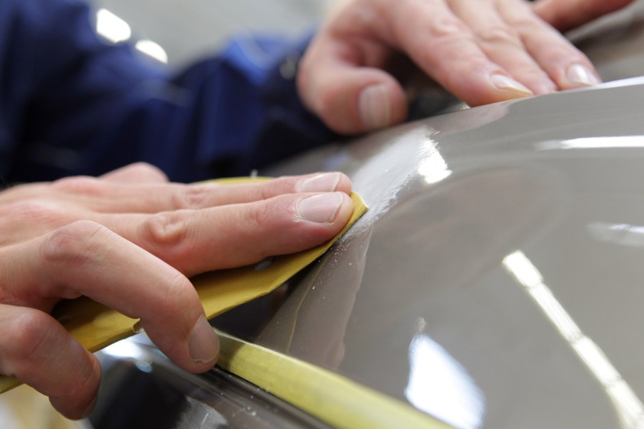 A detailer rubs compound on a car's paint