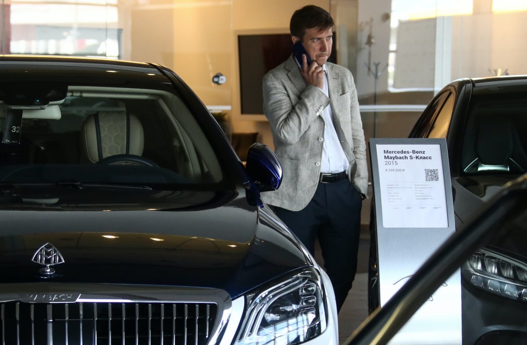 A car salesperson is on the phone on the showroom floor.