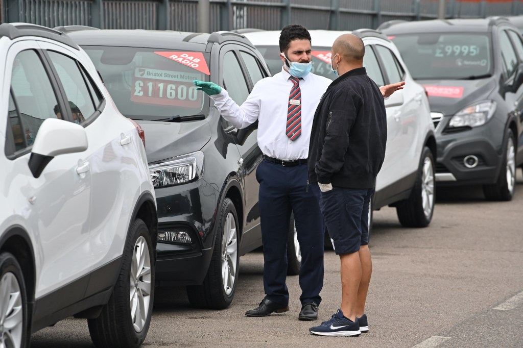 a car salesman talks to a customer on the sales lot