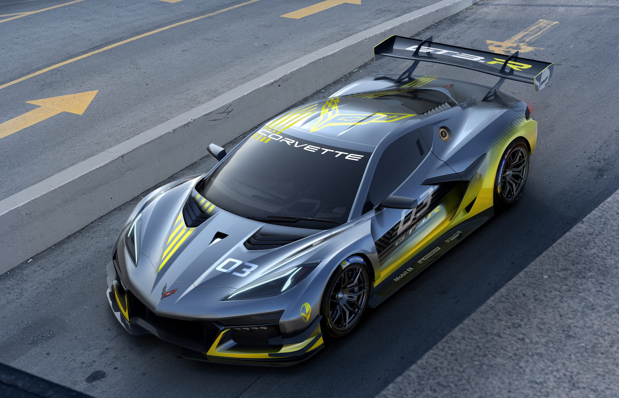 A grey and yellow Chevrolet Corvette C8.R race car shot from the high 3/4 angle in the pit lane
