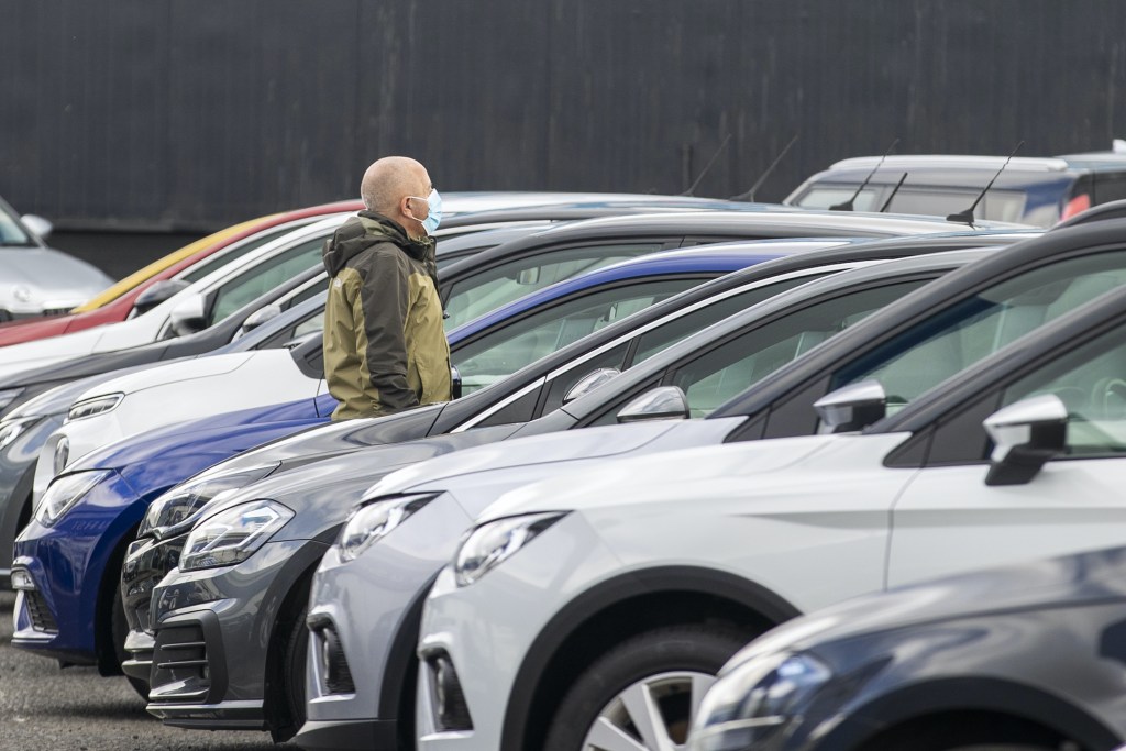 A potential customer walks around a used car dealership