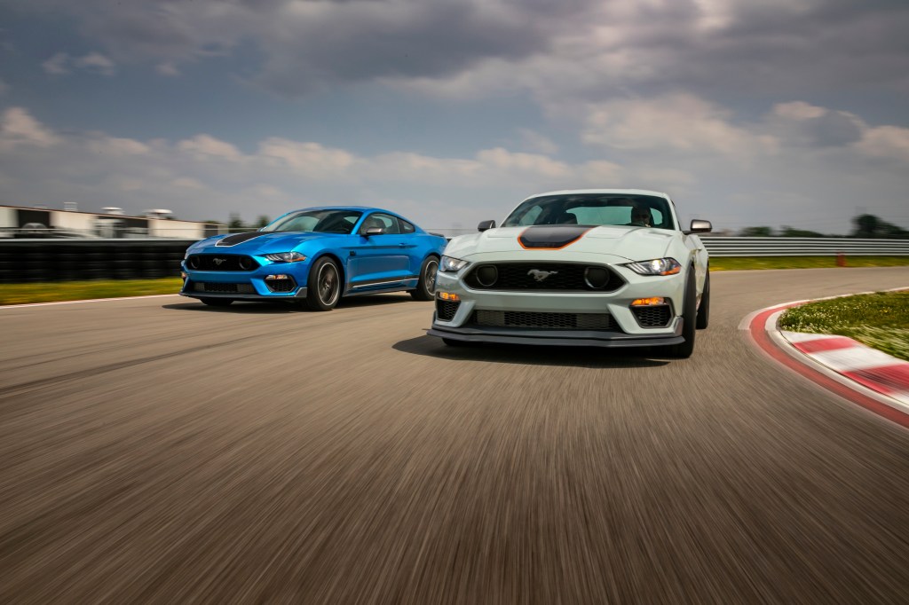 A pair of Ford Mustang Mach 1's in fighter grey and blue shot on a race track from the 3/4 angle