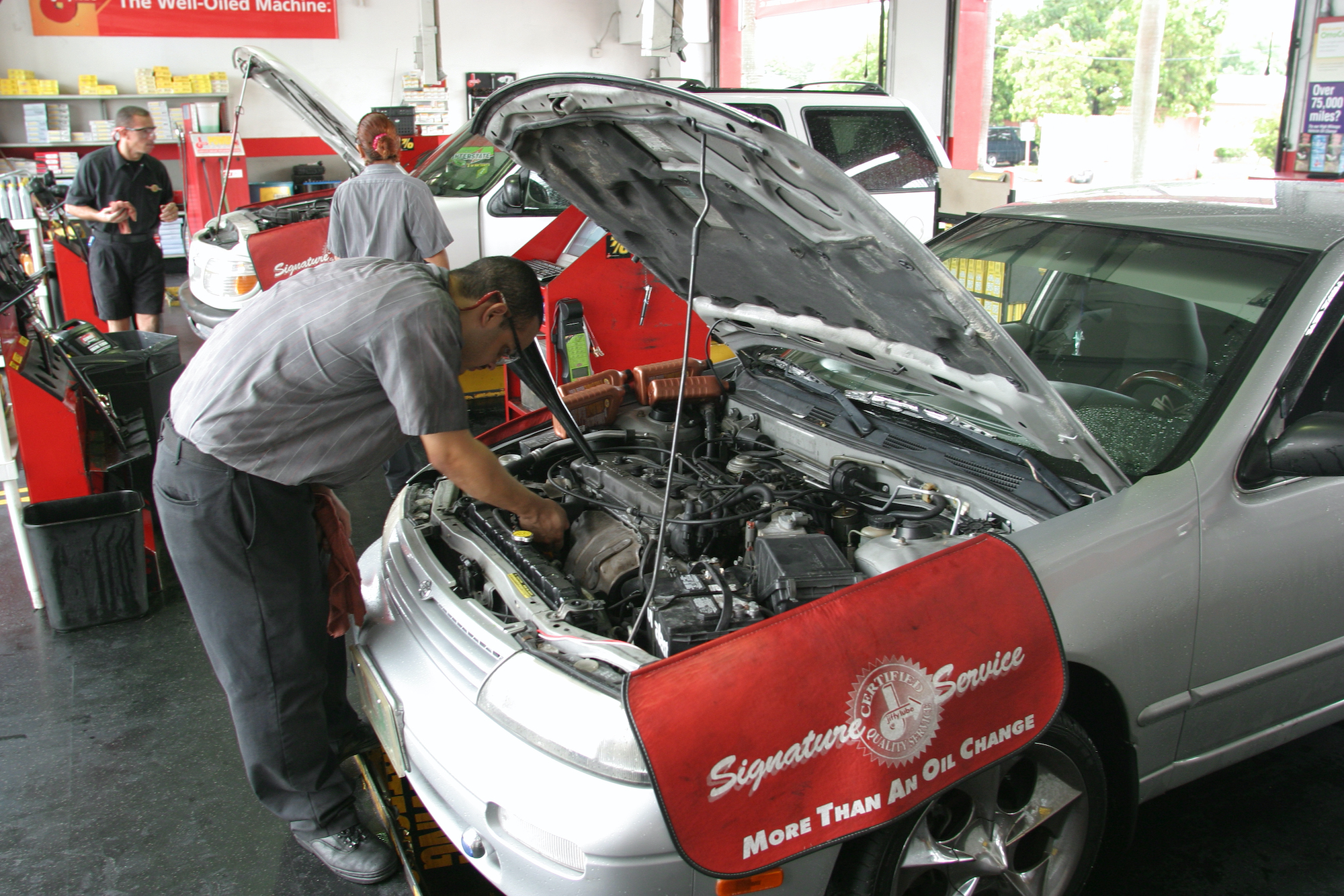 A Jiffy Lube mechanic changes the oil on a customer