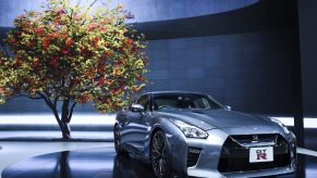 A silver Nissan GT-R shot from under a tree at an auto show