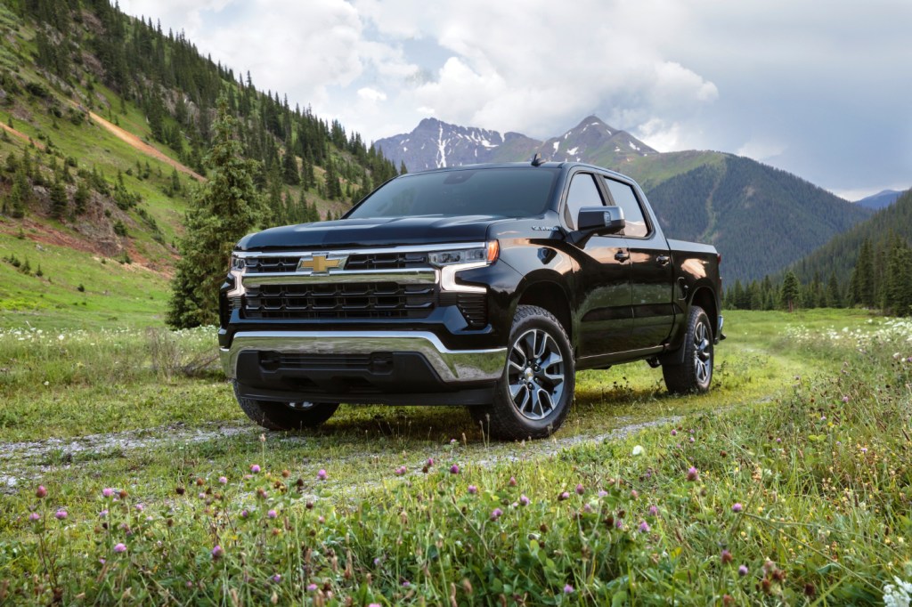 A black 2022 Chevrolet Silverado parked on grass with a mountainous background