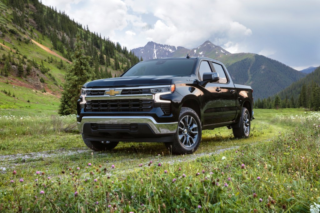 A black 2022 Chevy Silverado parked on grass with a mountainous background