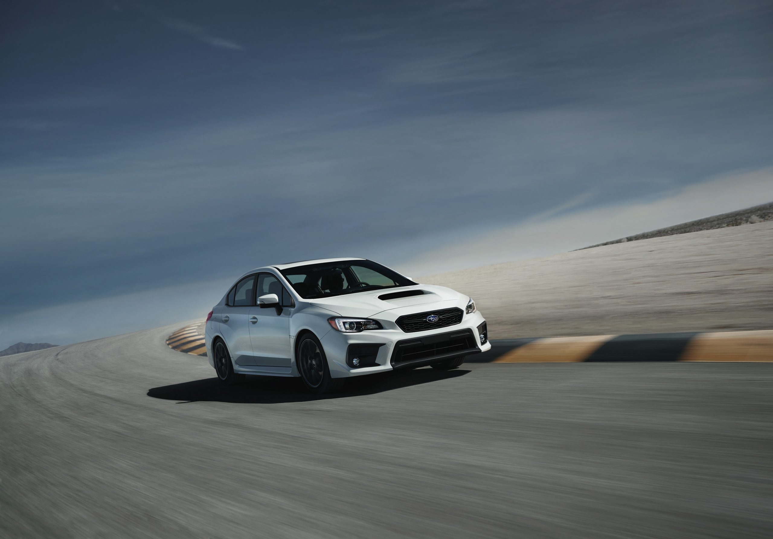 A white 2021 Subaru WRX shot from the front 3/4 on a race track