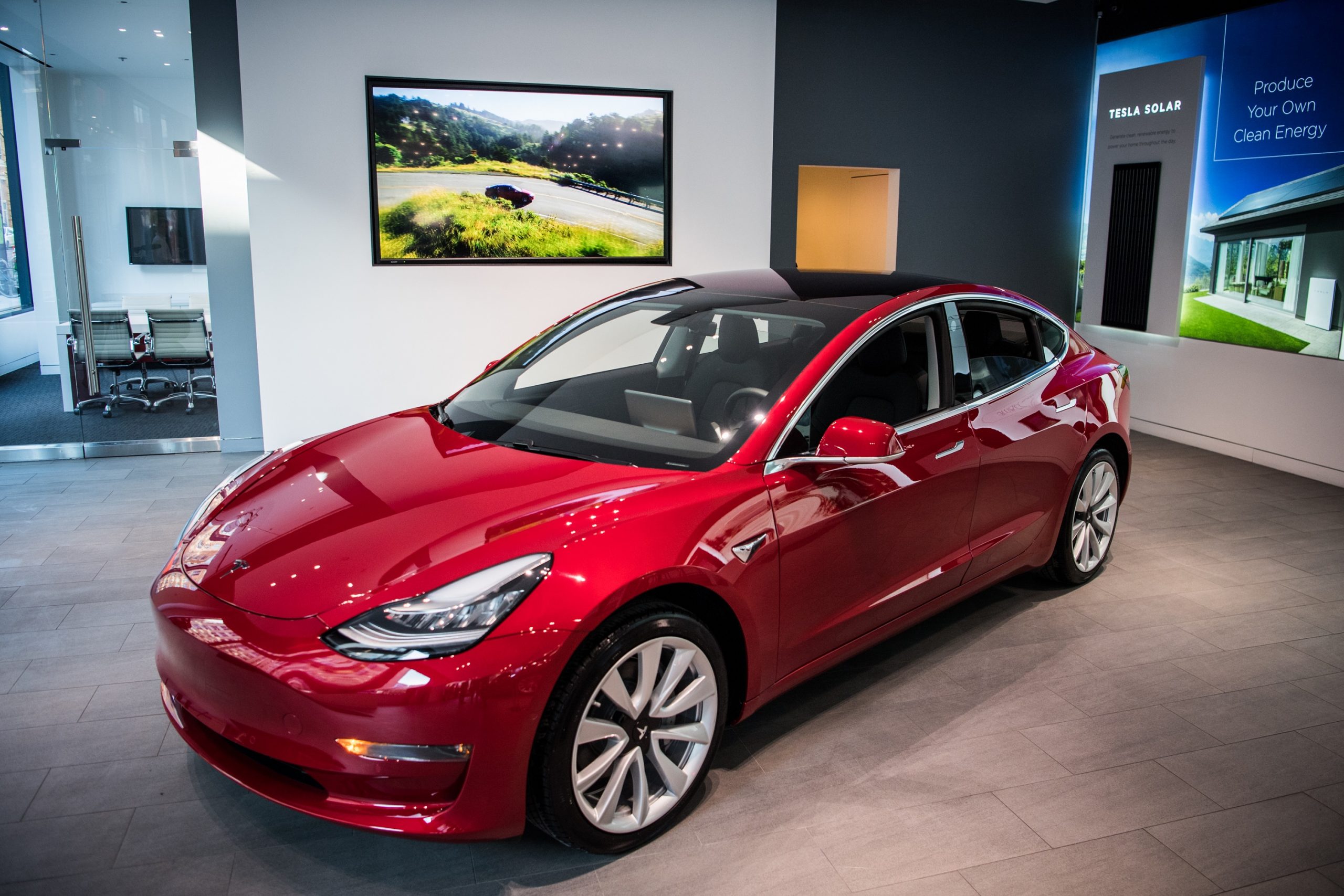 A red Tesla Model 3 EV shot from the high front 3/4 angle 