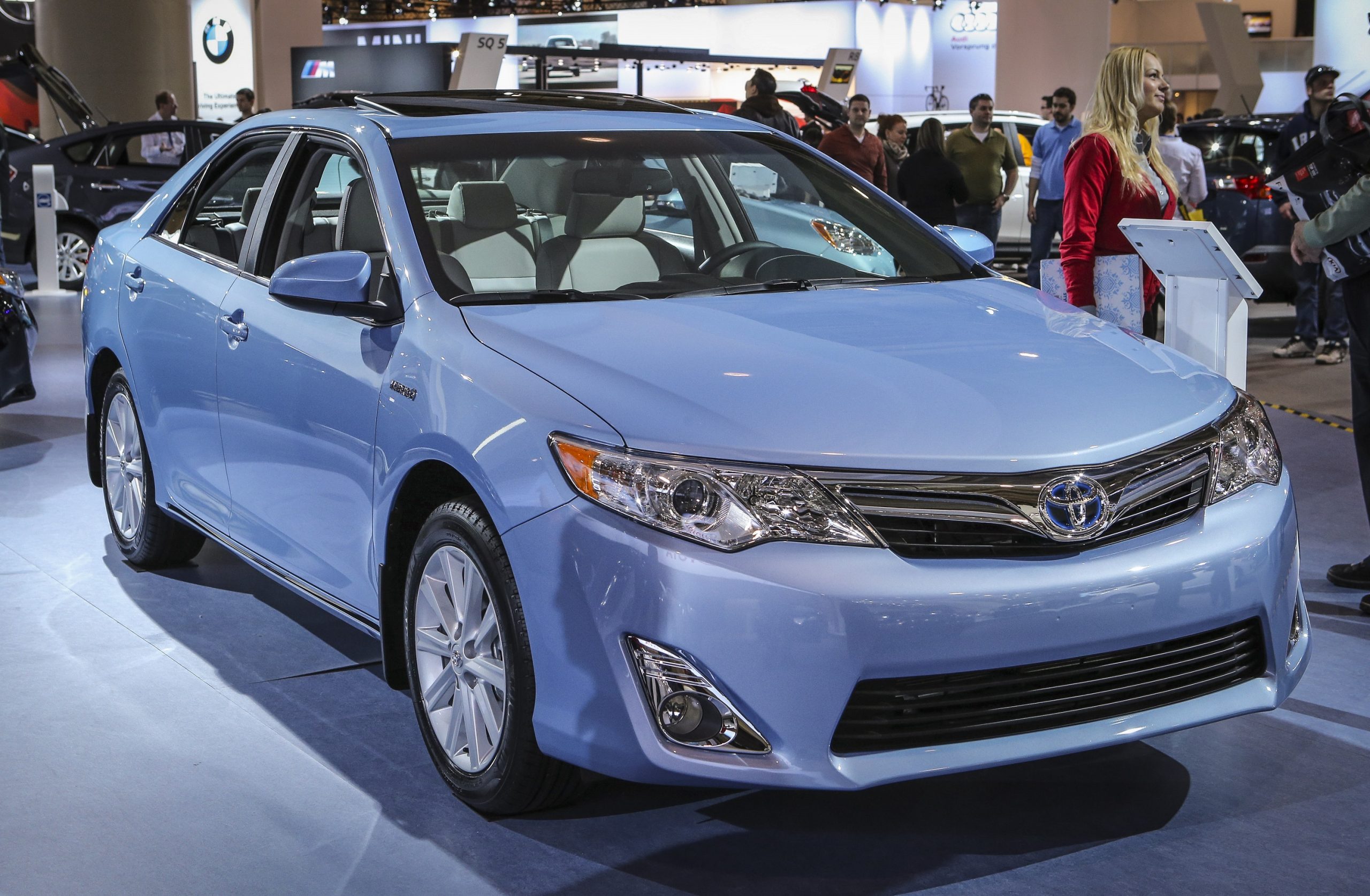 A blue Toyota Camry sedan shot from the 3/4 angle at an auto show