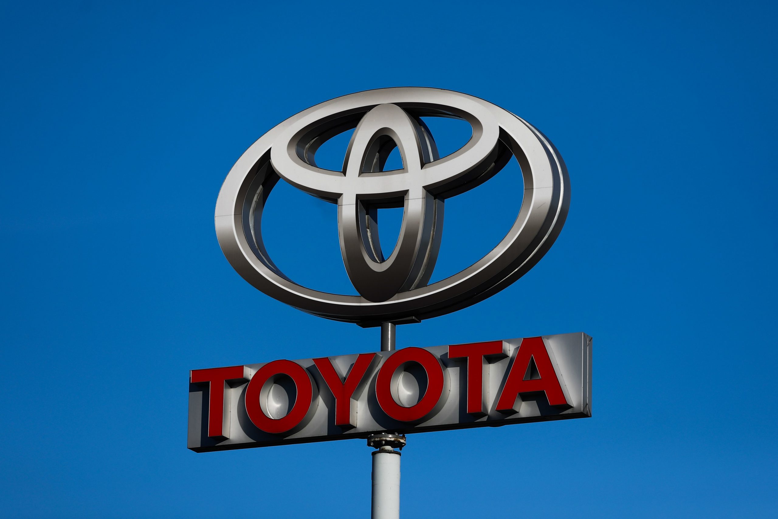 A Toyota logo displayed on a signpost outside a dealership
