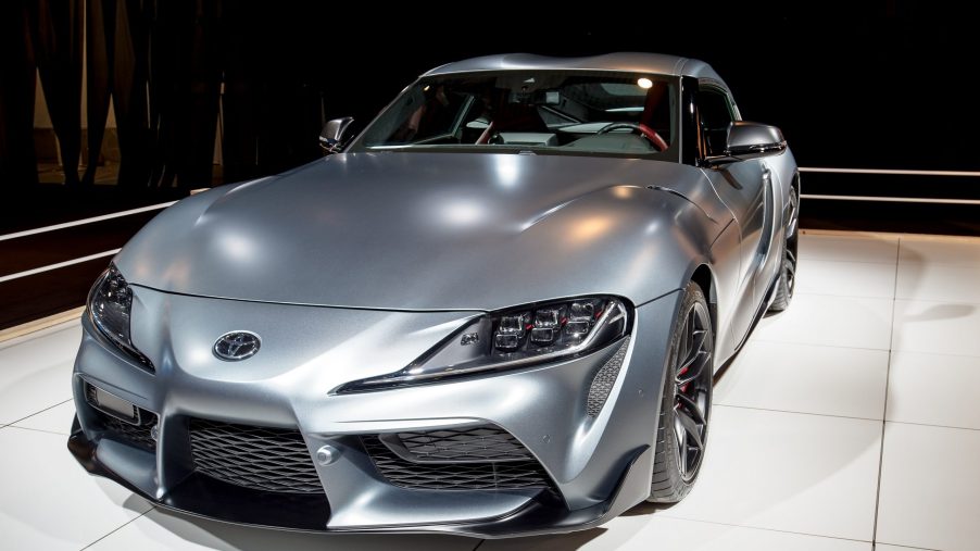 A matte grey Toyota Supra shot from the 3/4 angle at an auto show