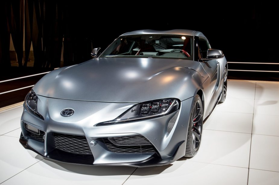 A matte grey Toyota Supra shot from the 3/4 angle at an auto show