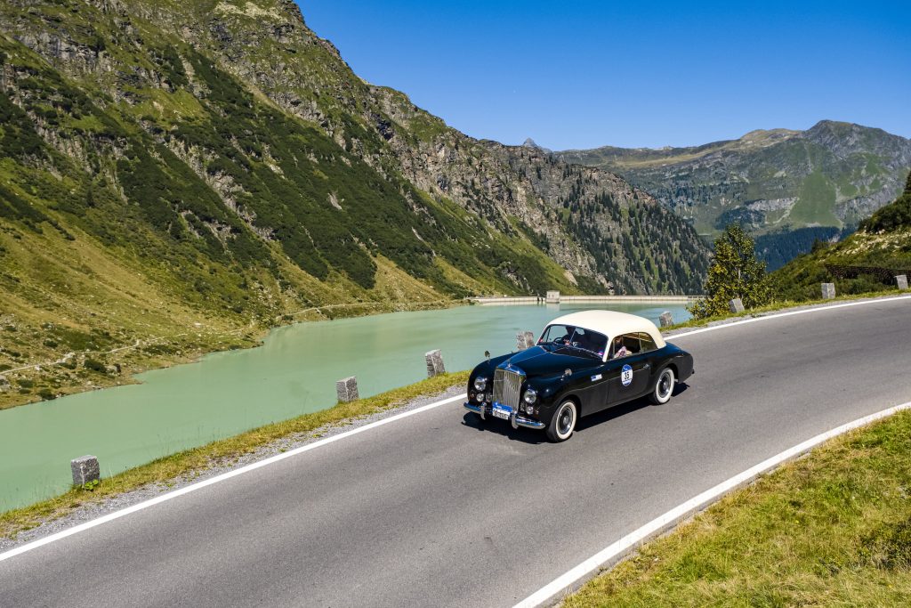 a classic Bentley drives along a river