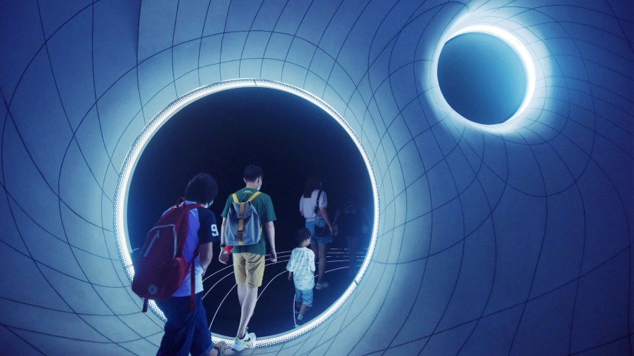 a group of kids walk through a wormhole exhibit in china