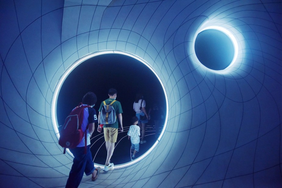 a group of kids walk through a wormhole exhibit in china