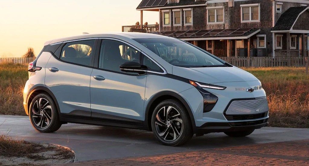 A silver 2022 Chevy Bolt is parked outside of a house. 