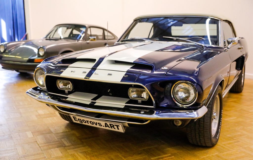 A blue-with-white-stripes 1968 Ford Mustang Shelby GT500KR Convertible