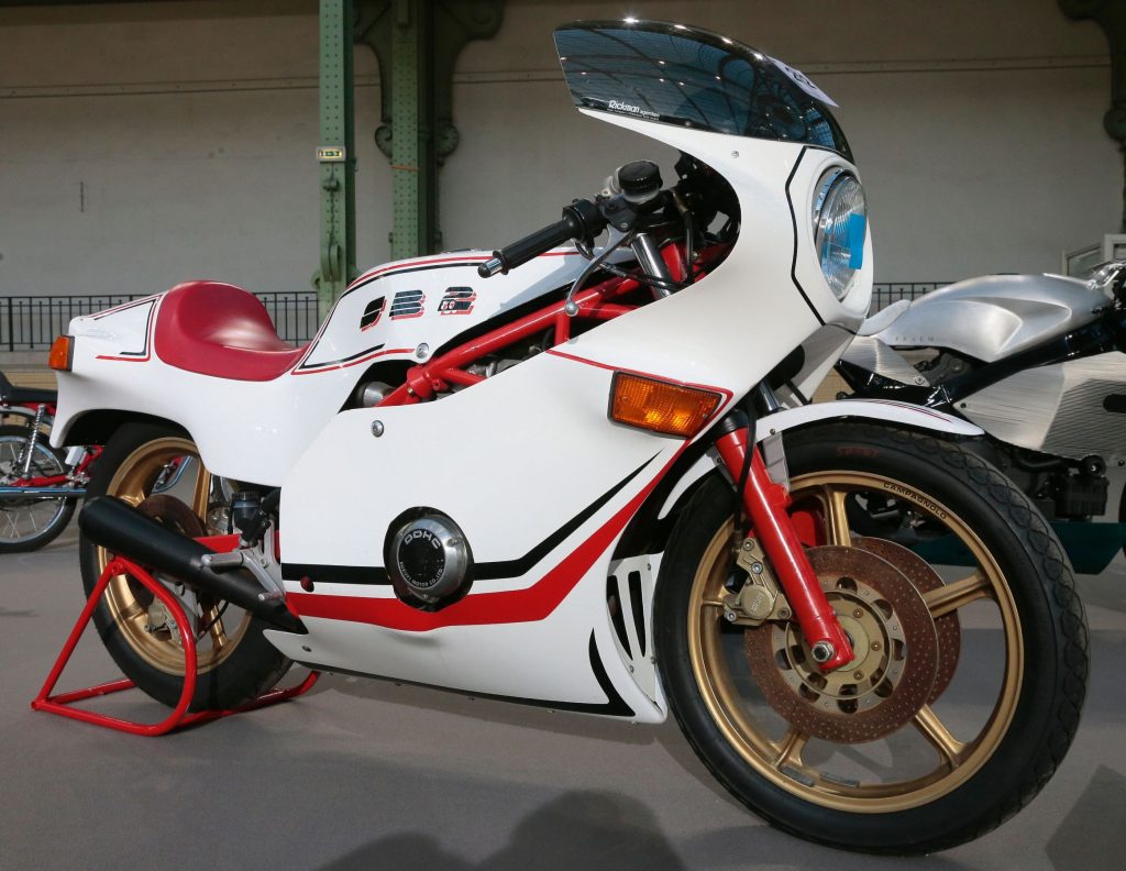 A white-with-red-and-green-stripes 1980 Bimota SB2/80 on a red rear-wheel stand