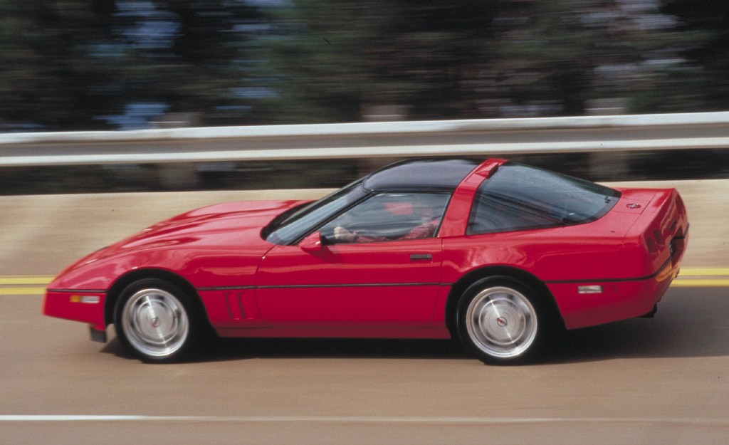 The side view of a red 1990 Chevrolet C4 Corvette ZR1 driving around a racetrack