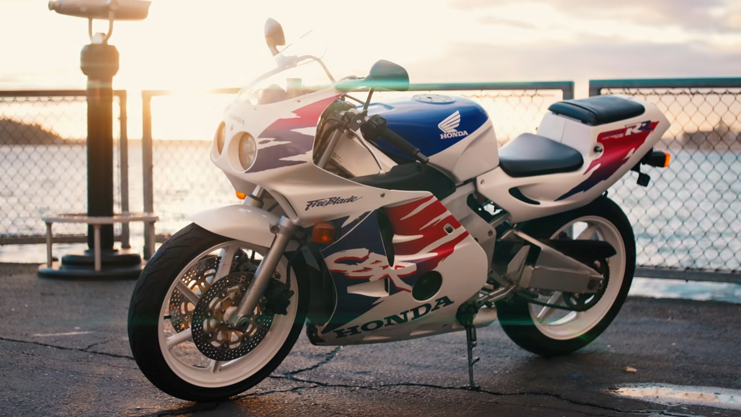 The left-side view of a white-red-and-blue 1992 Honda CBR250RR 'MC22' parked by the ocean