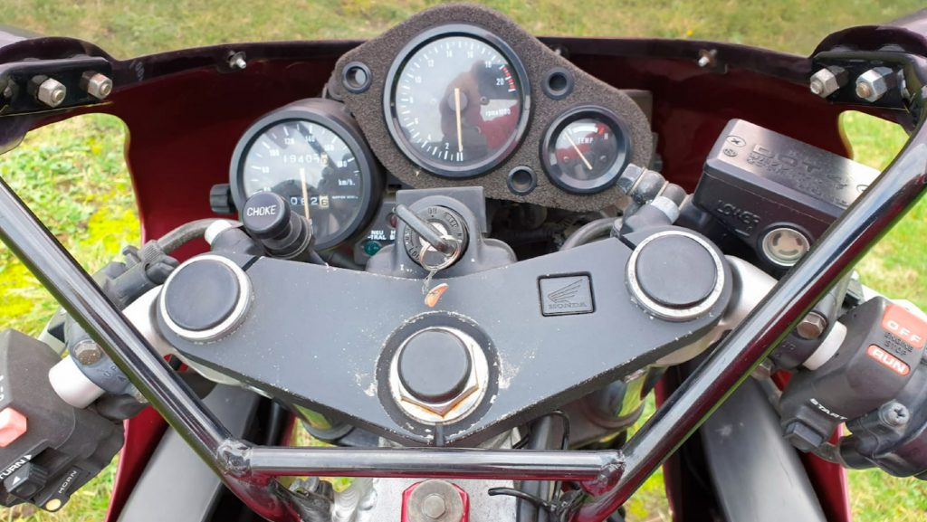 The black gauges, controls, and fork tops on a red 1992 Honda CBR250RR