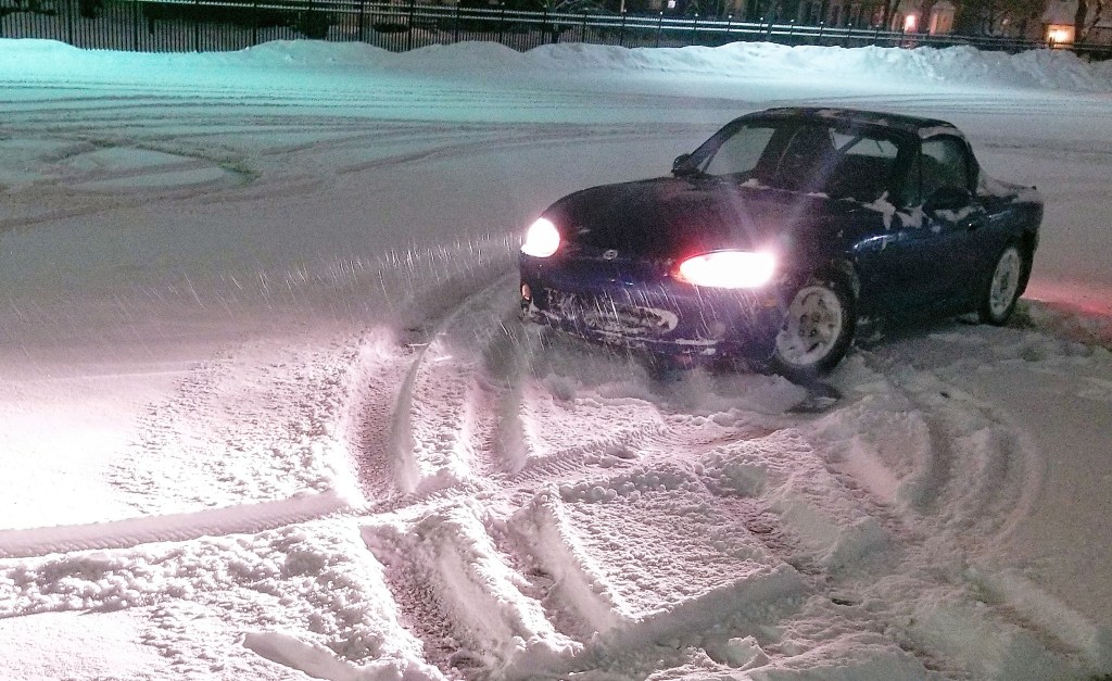 A blue 1999 Mazda MX-5 Miata 10th Anniversary Edition on winter tires in a snowy parking lot