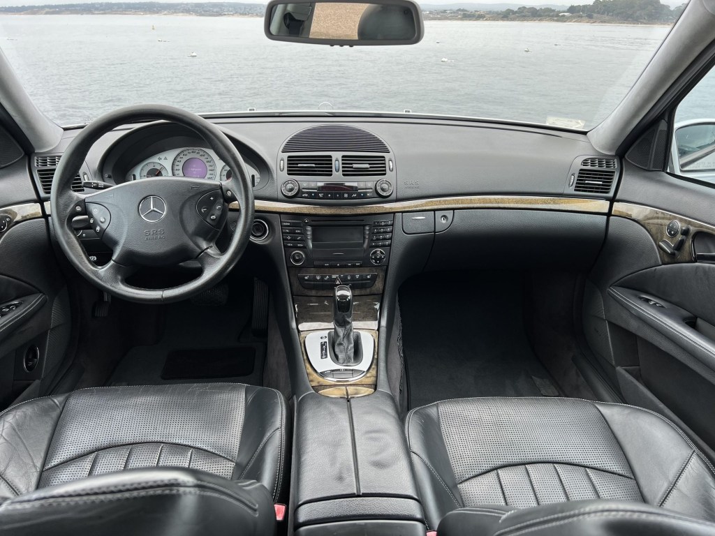 The black-leather-upholstered front seats and wood-trimmed dashboard of a 2003 Mercedes-Benz E55 AMG
