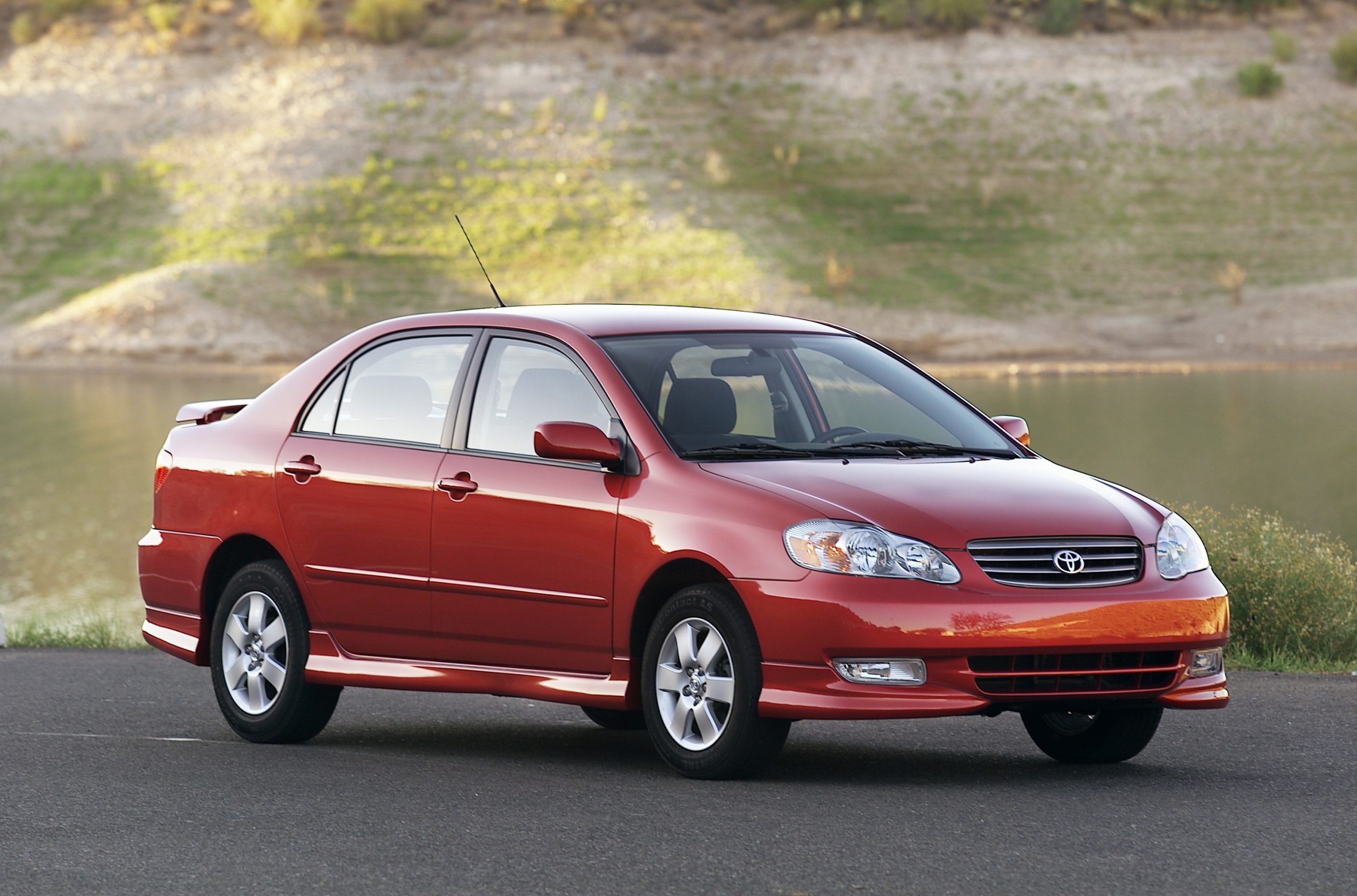 A red '05 Toyota Corolla shot from the front 3/4 during the golden hour