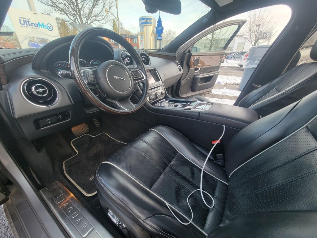The black-leather-upholstered front seats and black-leather-and-wood-trimmed dashboard of a 2011 Jaguar XJ Supercharged