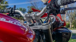 A close-up view of a red 2012 Triumph Street Triple R's aluminum handlebar with SW-MOTECH risers