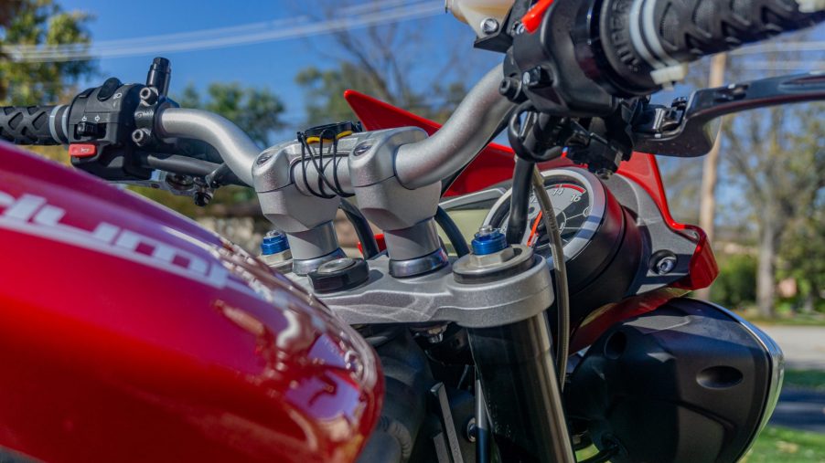 A close-up view of a red 2012 Triumph Street Triple R's aluminum handlebar with SW-MOTECH risers