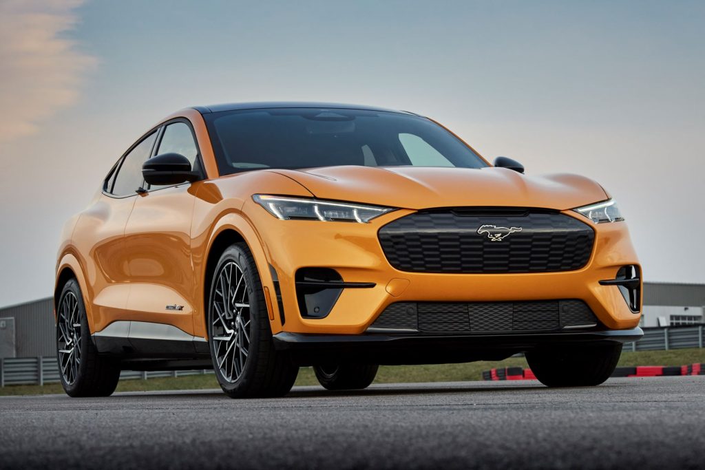 A 2021 Ford Mustang Mach-E GT all-electric compact SUV model with a gold color option parked on a race track