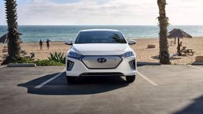 A 2021 Hyundai Ioniq Electric liftback with a white paint color option parked at a beach