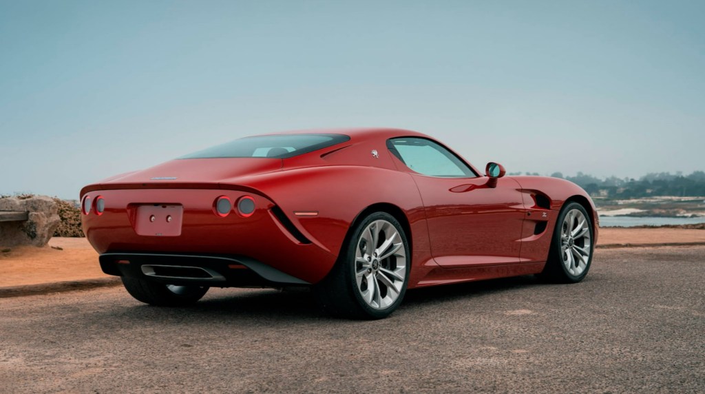 The rear 3/4 view of a red 2021 Iso Rivolta GT Zagato by the ocean