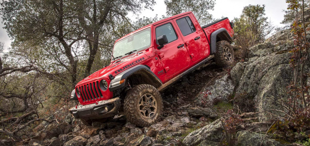 A 2021 Jeep Gladiator midsize pickup truck driving down a rocky cliff in the wilderness, it just gained new upgrades.