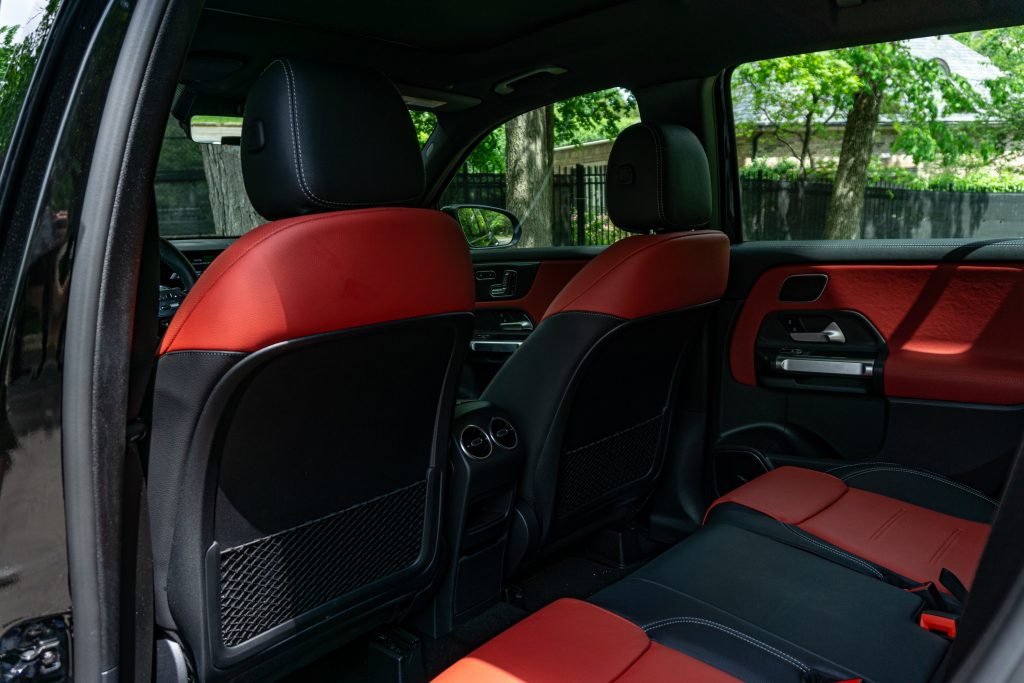 The red-and-black-leather-upholstered interior of a black 2021 Mercedes-AMG GLB 35 interior seen from the rear door