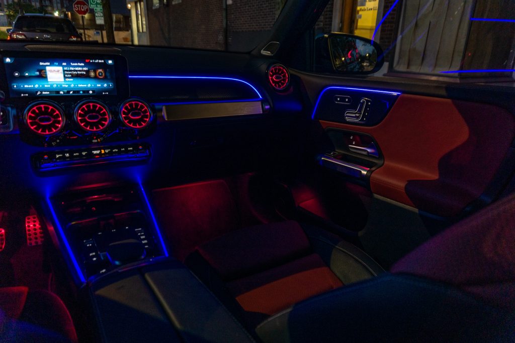 The red-and-black-leather-upholstered 2021 Mercedes-AMG GLB 35 passenger-side front interior with blue-and-red ambient lighting