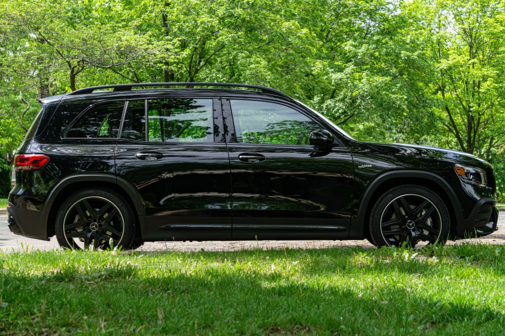 The side view of a black 2021 Mercedes-AMG GLB 35 in a forest parking lot