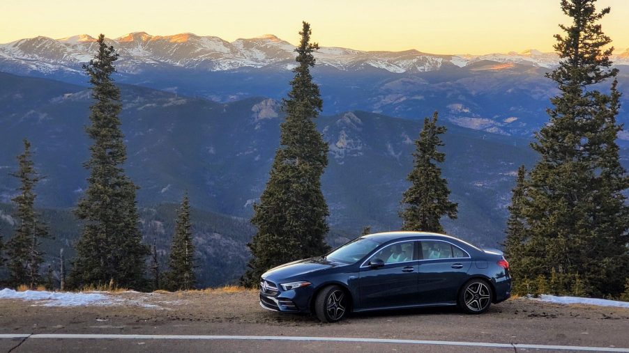 A Denim Blue Mercedes-AMG A35 sedan shot in profile on a mountain pass at sunset