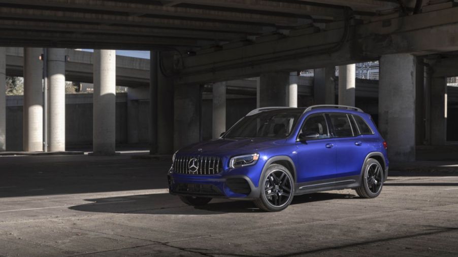 A 2021 Mercedes-Benz AMG GLB SUV with a blue paint color option parked under a concrete highway overpass