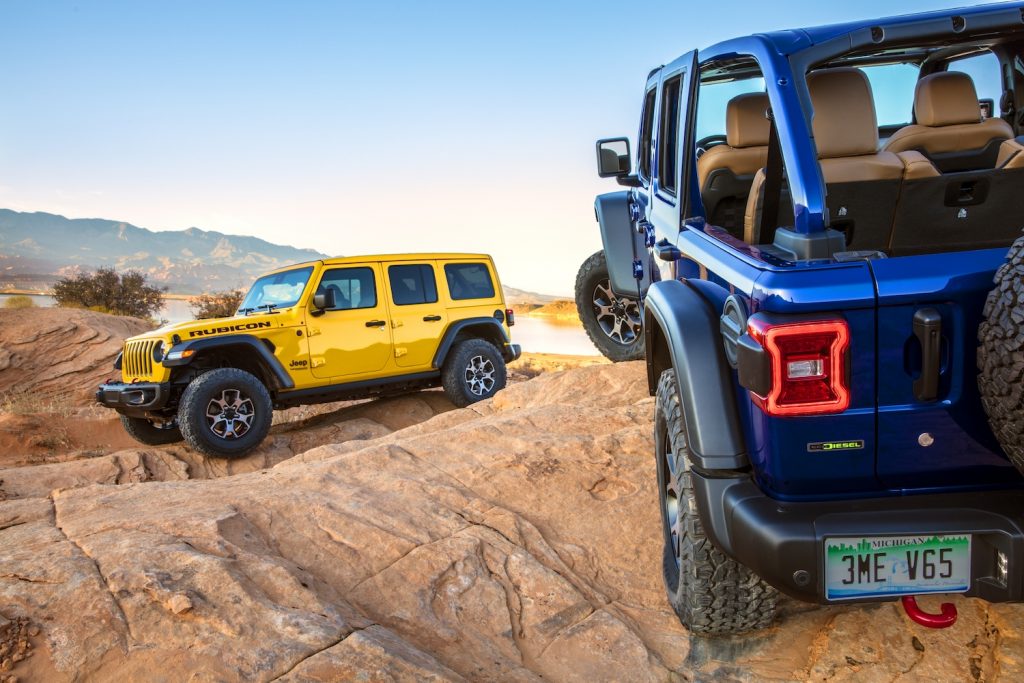 A yellow and blue Jeep Wrangler Rubicon drive together along a dirt road, is it better than the Ford Bronco Wildtrak?