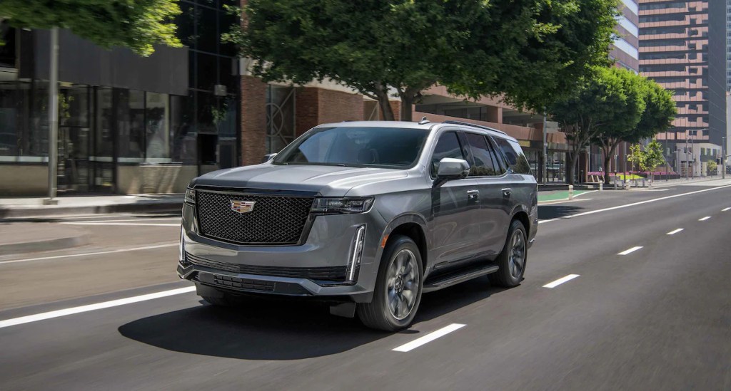 A gray 2022 Cadillac Escalade sport Platinum drives along a road during the day with buildings in the background, is it worth the price of more than $100,000?