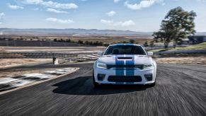 The 2022 Dodge Charger Jailbreak muscle car model with the Old Glory hood stripe paint color option driving on a race track
