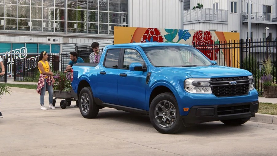A blue 2022 Ford Maverick outisde with people around it.