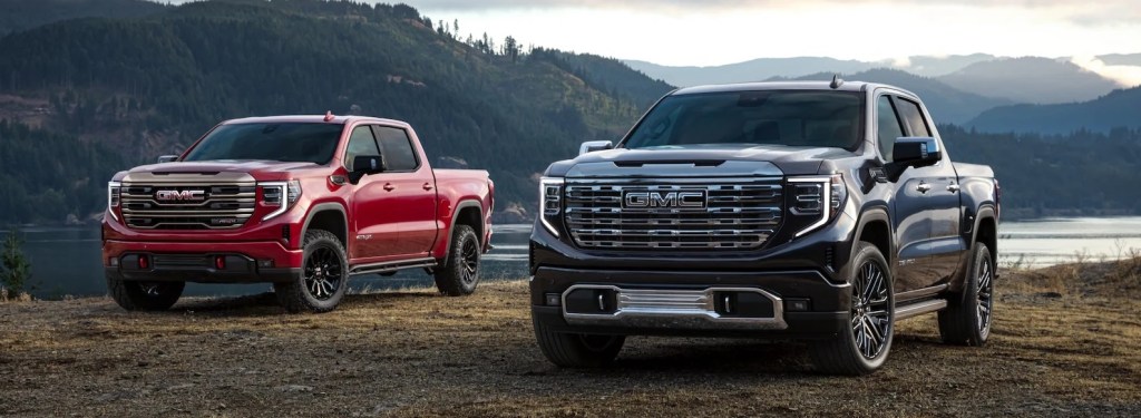 Two 2022 GMC Sierra 1500s parked in front of a lake.