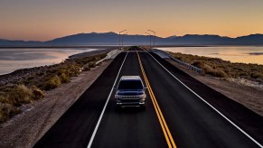A 2022 Jeep Grand Wagoneer driving down a highway at sunset.