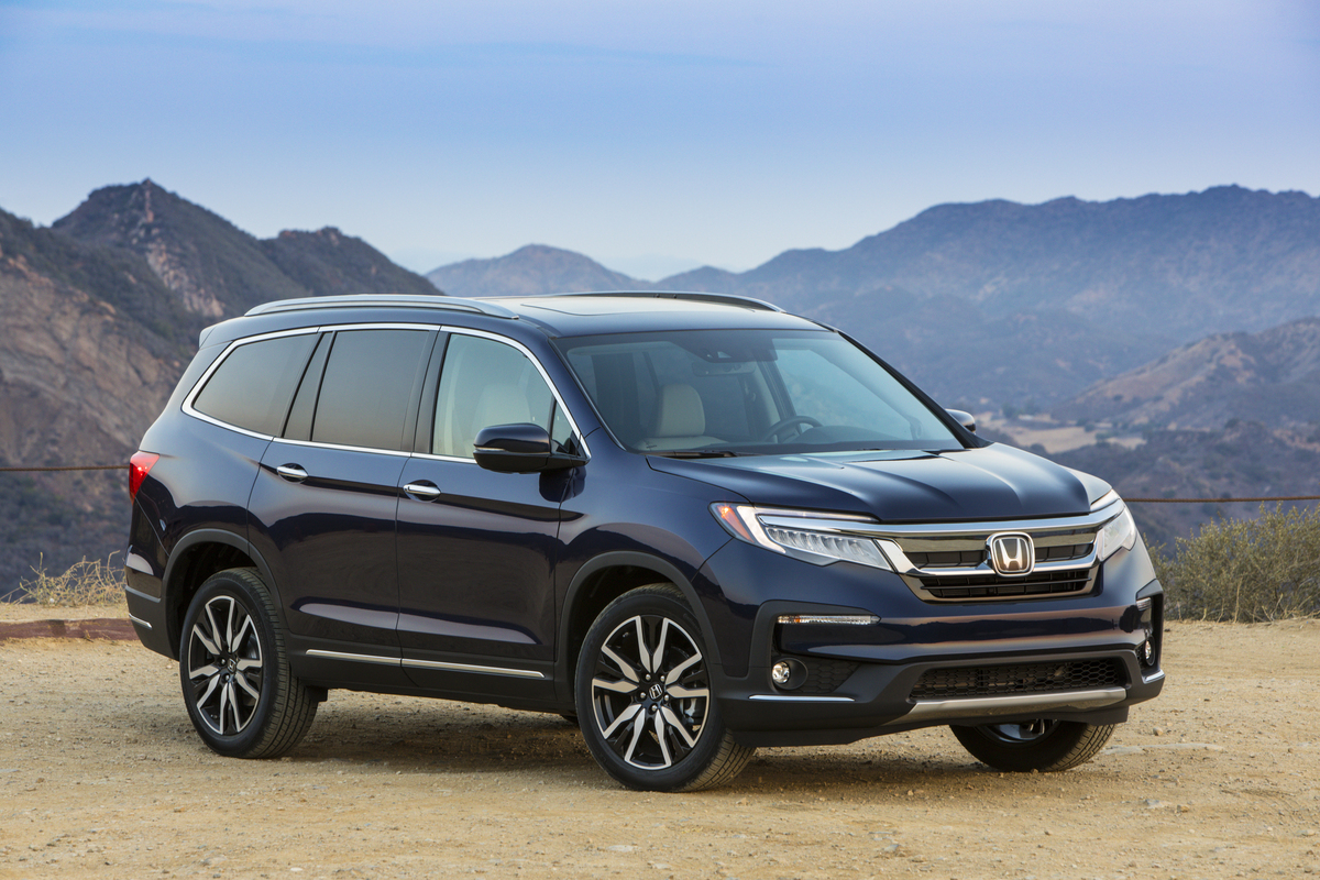 A navy blue 2022 Honda Pilot Elite parked on gravel in front of mountains on a clear day