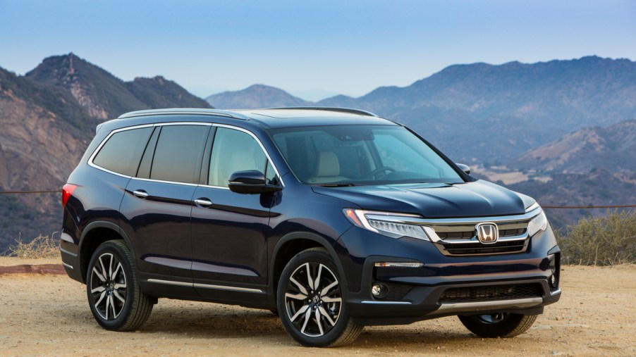 A navy blue 2022 Honda Pilot Elite parked on gravel in front of mountains on a clear day