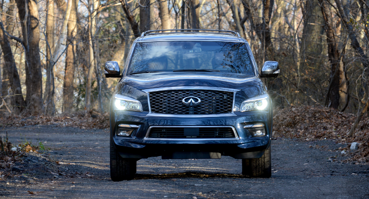 A blue 2022 Infiniti QX80 is parked outside in the woods.